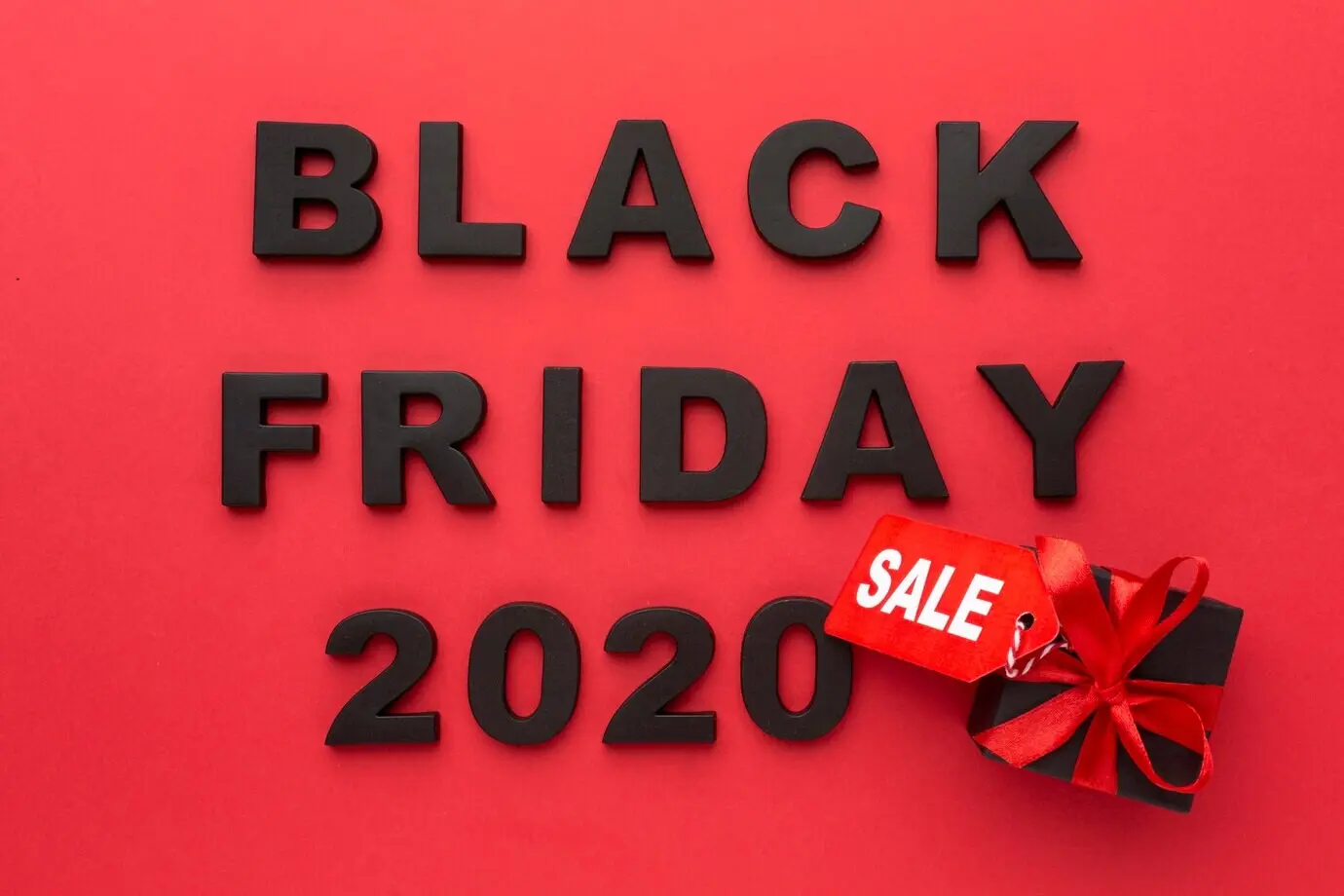 Overhead view of a Black Friday sales arrangement on a red background.